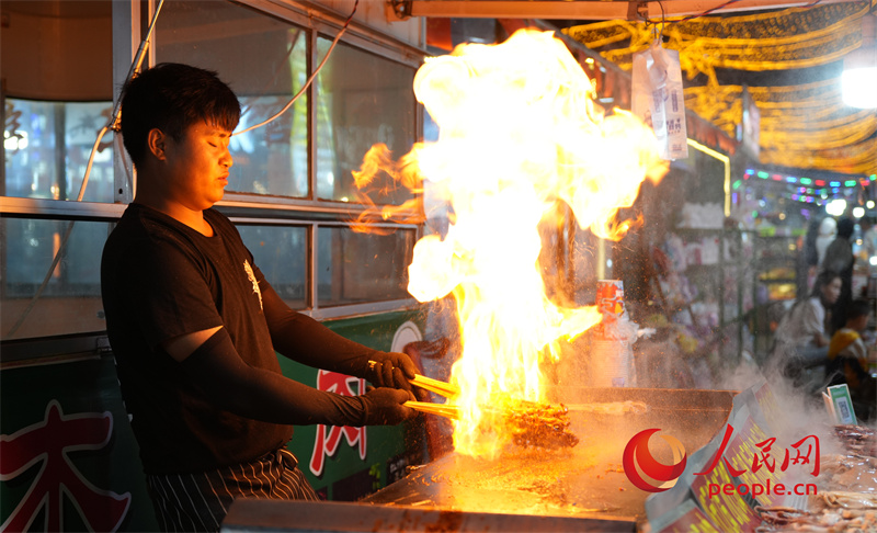 旱碼頭1960商業(yè)街內(nèi)火爆魷魚(yú)攤位的攤主正在忙活。人民網(wǎng)記者 甘海瓊攝