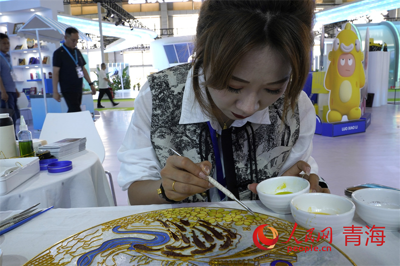 青洽會現(xiàn)場游客體驗掐絲唐卡技藝。人民網(wǎng)記者 甘海瓊攝