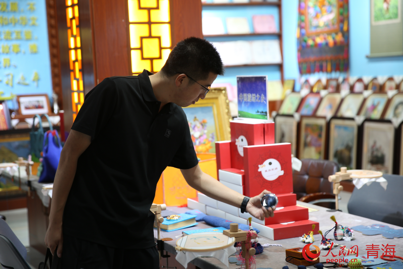 與會嘉賓了解海南州藏繡產(chǎn)品。人民網(wǎng) 馬可欣攝