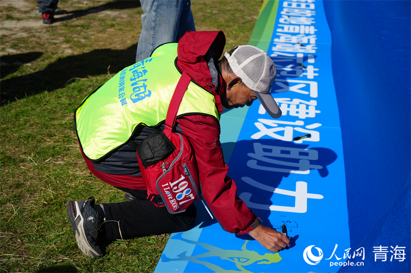 志愿者在橫幅上簽名。人民網(wǎng) 況玉攝