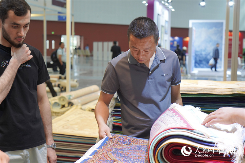 參展人員了解藏毯。人民網(wǎng)記者 張莉萍攝